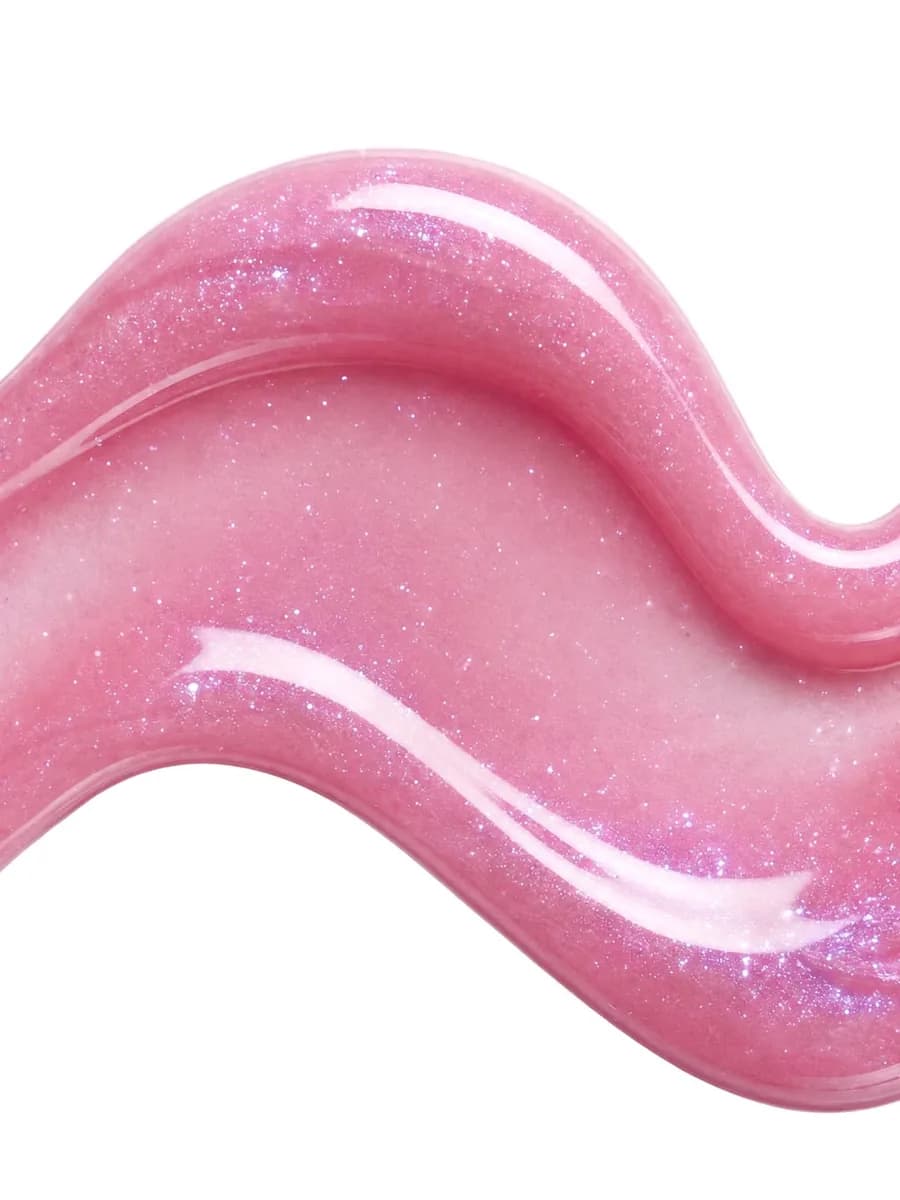 Mancha de gloss rosa translúcido com brilho perolado em close, mostrando a textura do produto